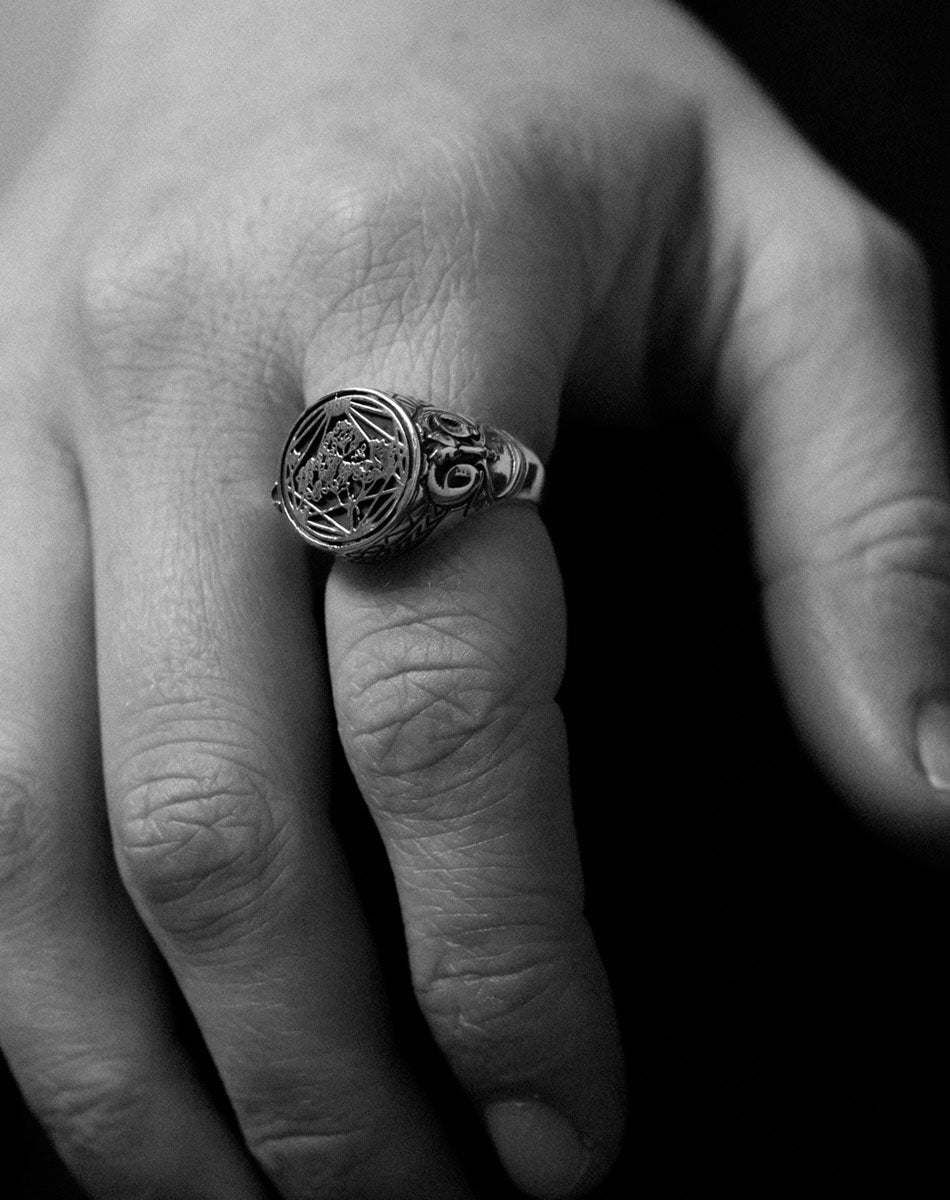 Chunky silver signet ring with etching details. Worn on a hand. 