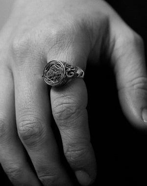 Chunky silver signet ring with etching details. Worn on a hand. 