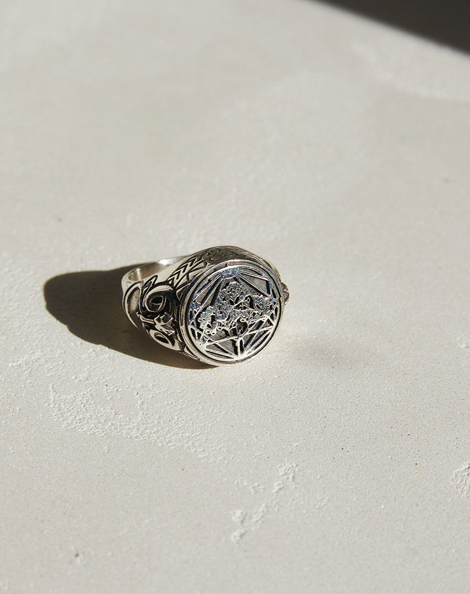A sterling silver ring featuring a heavy weighted design with a collage of artworks.