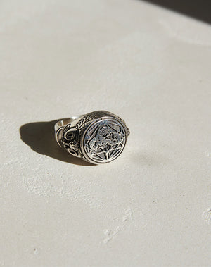 A sterling silver ring featuring a heavy weighted design with a collage of artworks.
