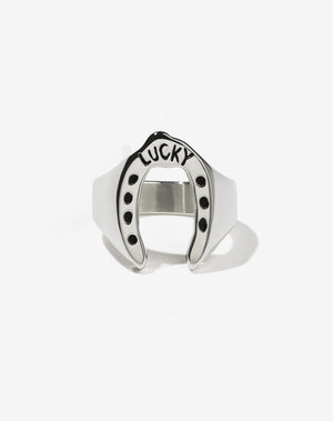 A sterling silver ring with a wide band that flares out into a shape resembling a lucky horseshoe, with the word 'LUCKY' inscribed
