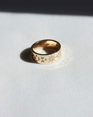 A yellow gold ring with ornate floral engravings set with diamonds throughout.