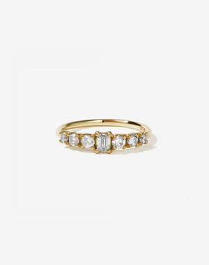 This beautiful and petite seven stone ring has a central emerald cut stone and is flanked by three ascending sized round brilliant diamonds on each shoulder.