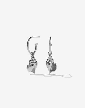 A pair of sterling silver hoop earrings with a conch charm attached to the hoop.