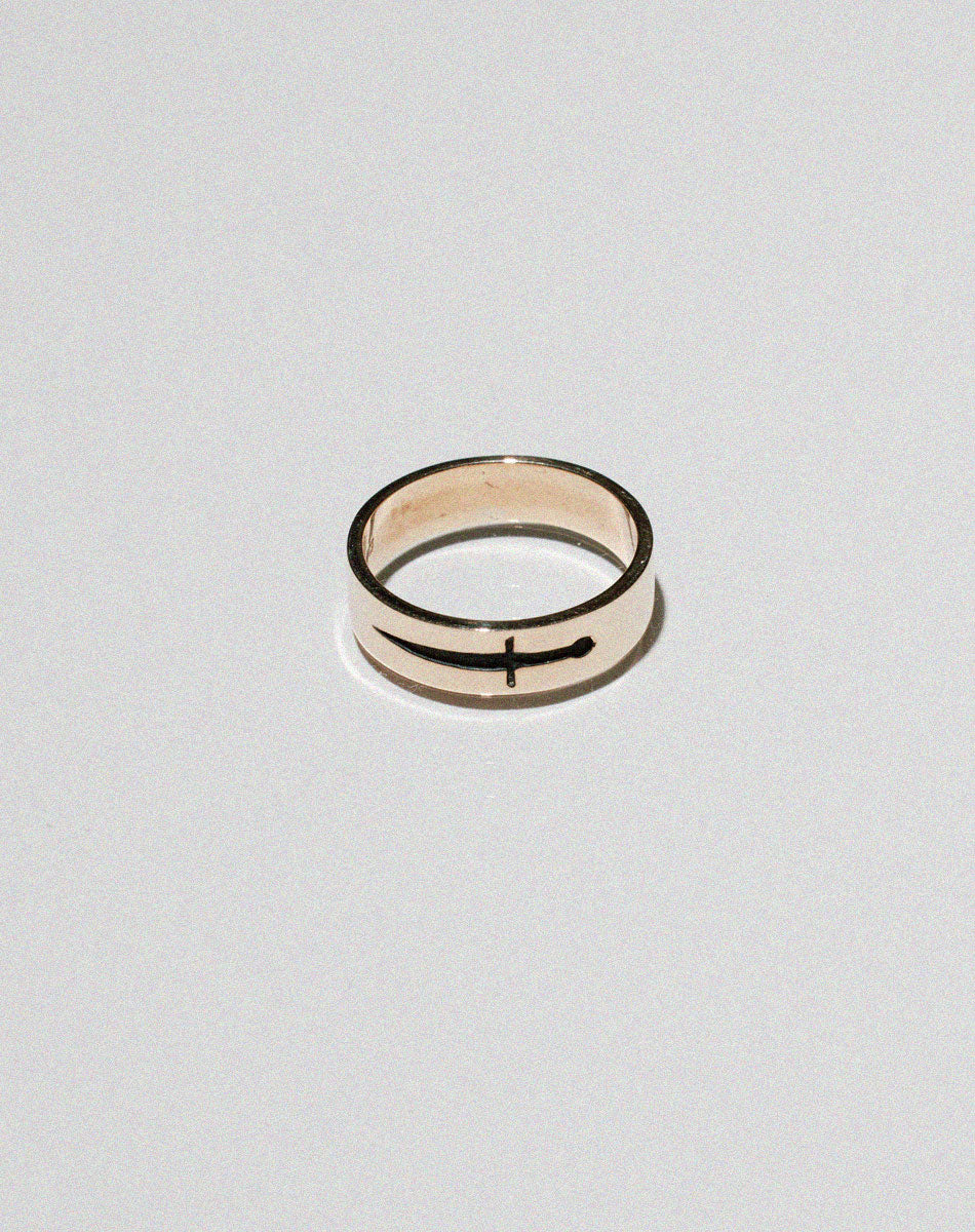 A gold ring featuring an etched and oxidised dagger design on a band.