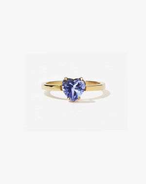 A gold ring with a heart-shaped cut tanzanite stone set in a simple claw setting on a delicate band.
