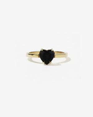 A gold ring with a heart-shaped cut onyx stone set in a simple claw setting on a delicate band.