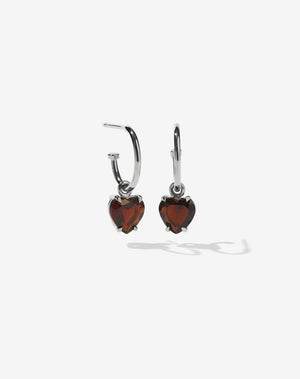A pair of sterling silver hoop earrings with heart-shaped Thai garnet stones set in a claw setting.