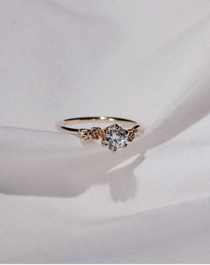 Meadowlark Jewellery’s iconic Alba Engagement Ring in 9ct Yellow Gold, claw set with a 0.50ct round brilliant cut white diamond. Round band adorned with flowers, set with round brilliant cut white diamonds. Pair with our bestseller, the Alba Band Stone Set or Plain. Made in New Zealand. Still image.
