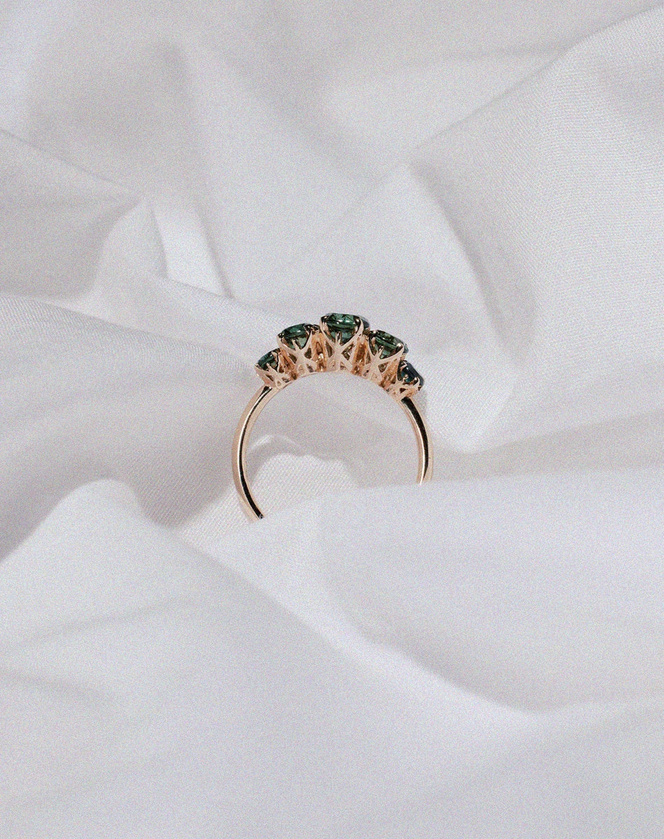 Meadowlark Jewellery’s classic Signature 5 Stone Engagement Ring in 9ct Yellow Gold, with round brilliant cut green sapphire. Fully traceable and ethically sourced blue and green sapphires from Queensland, Australia. Set into our signature Meadowlark claw setting, featuring graphic lines inspired by our insignia. Pair with our bestseller, the Amelie Band Pave or Plain. One of our most timeless and beloved Ceremonial designs, made in New Zealand.