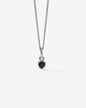 A sterling silver necklace featuring a small heart-shaped garnet stone in a claw setting, suspended from a fine chain.