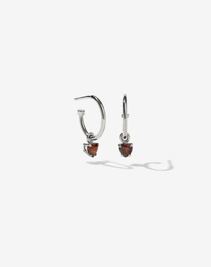 A pair of sterling silver hoop earrings with heart-shaped Thai garnet stones set in claw settings.