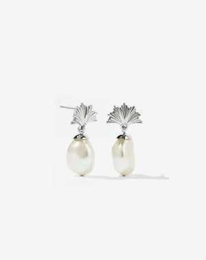 A pair of sterling silver drop earrings featuring a fan-shaped ginko leaf design atop a large freshwater pearl.